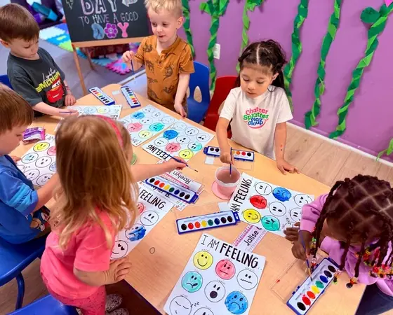 Children painting feelings charts during a learning activity at Chatter Splatter Daycare