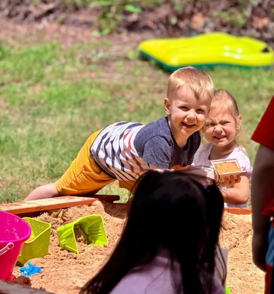 Children playing in the outdoor sandbox at Chatter Splatter Daycare