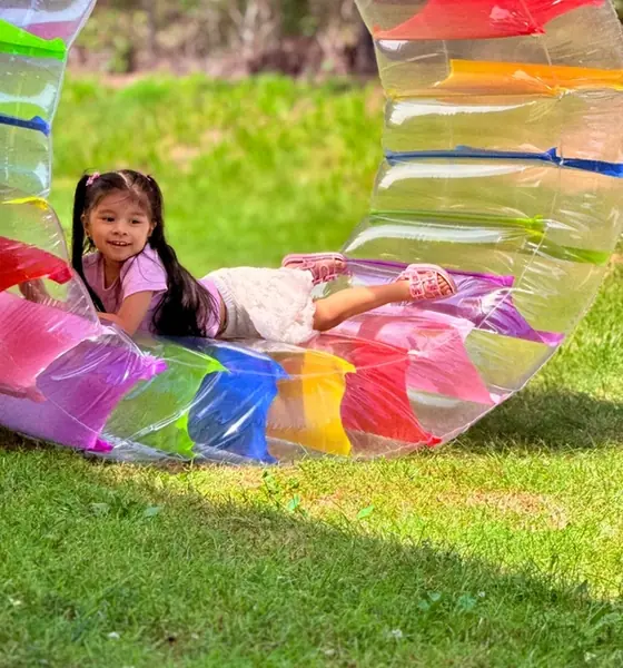 Child playing in a colorful outdoor play tunnel at Chatter Splatter Daycare
